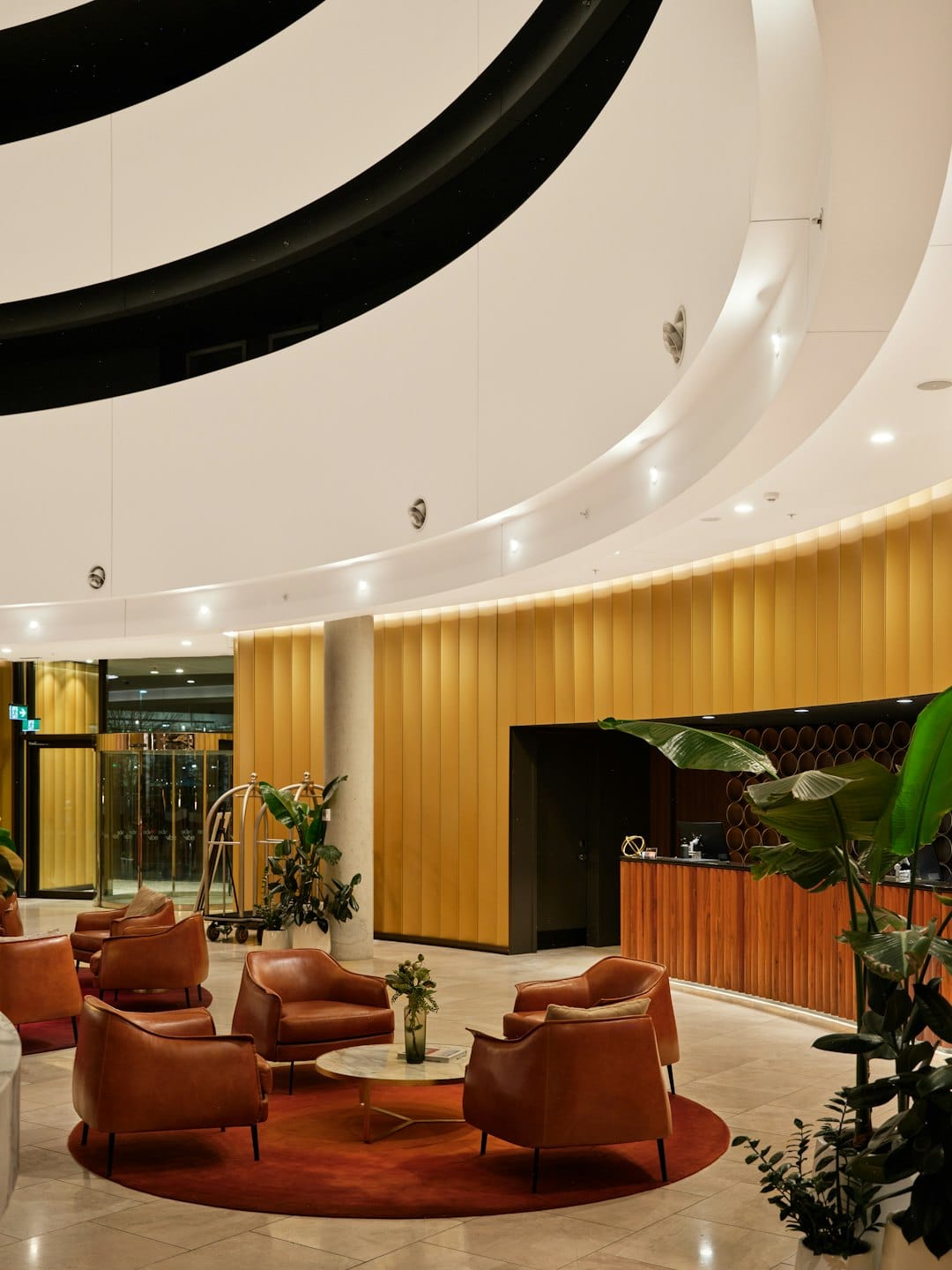 Moderne Hotellobby mit Ledersesseln um einen roten Teppich.